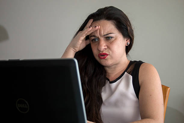 grave mulher trabalhando em seu laptop no escritório em casa de trabalho - efficency - fotografias e filmes do acervo