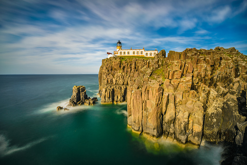 Rocky coastline of Lands End, Cornwall, UK, with the arch, Enys Dodnan, and the rock formation The Armed Knight, with the Longships Lighthouse offshore.