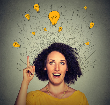 Closeup excited woman with many ideas light bulbs above head looking up pointing finger up isolated on gray wall background. Eureka creativity concept