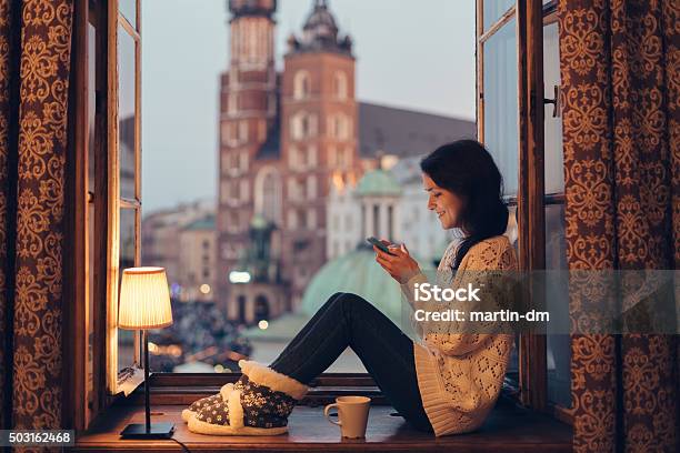 Woman Texting On The Window Sill Stock Photo - Download Image Now - Krakow, Poland, Window Sill