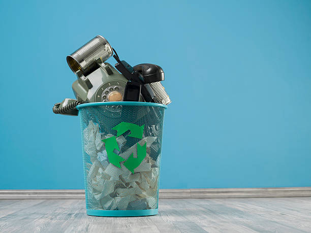 Old Fashioned Communication Tools In Trash Can On Turquoise Wall Old fashioned telephones, can phones, in trash can on the floor.The background is turquoise.There is a recycling sign on can.Copy space on the right side of frame.No people are seen in photo.Shot with a medium format camera Hasselblad i studio. toy phone stock pictures, royalty-free photos & images