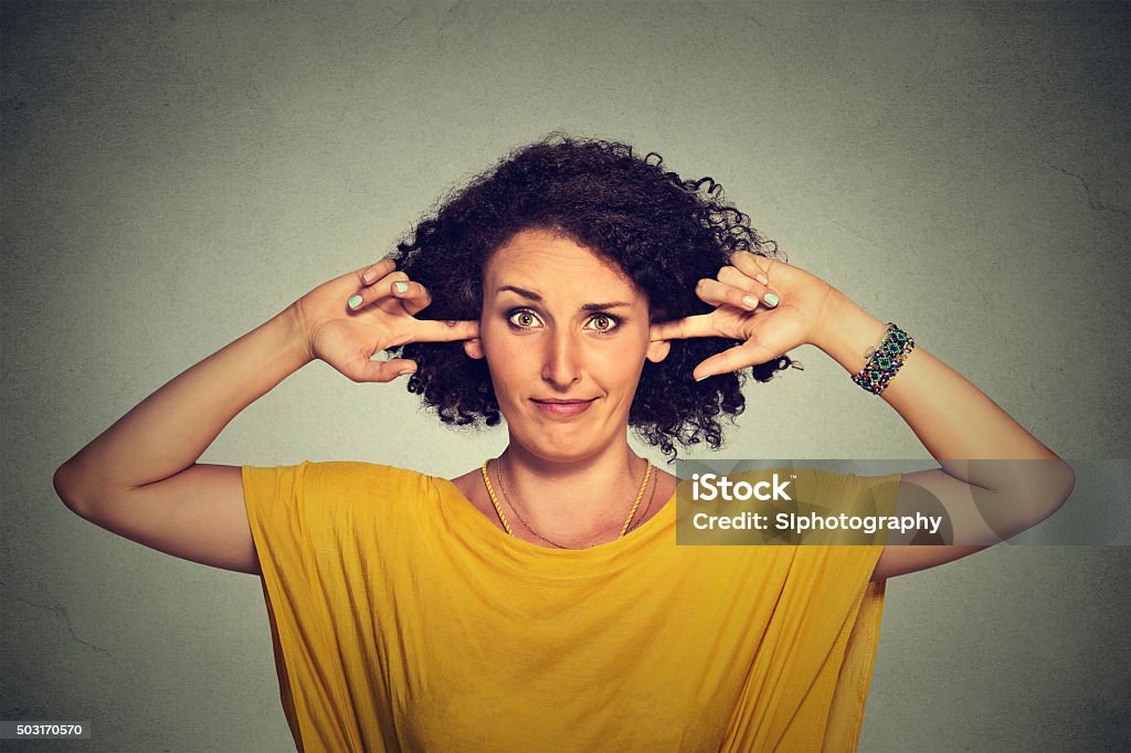 Annoyed woman plugging ears with fingers doesn't want to listen Annoyed upset angry woman plugging her ears with fingers doesn't want to listen Ignoring Stock Photo