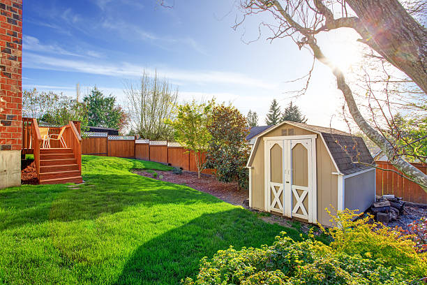 Fenced backyard with small shed Fenced backyard with wooden walkout deck and small shed shed stock pictures, royalty-free photos & images