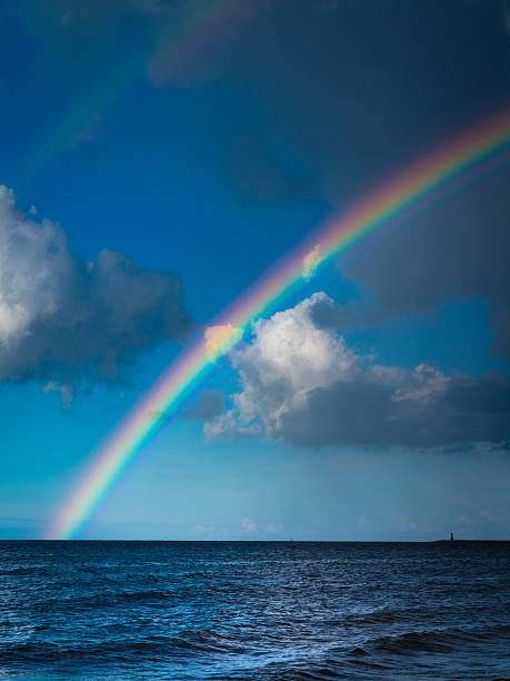 landscape view on cloudy sky with colorful rainbow at sea or ocean outdoor. Weather.