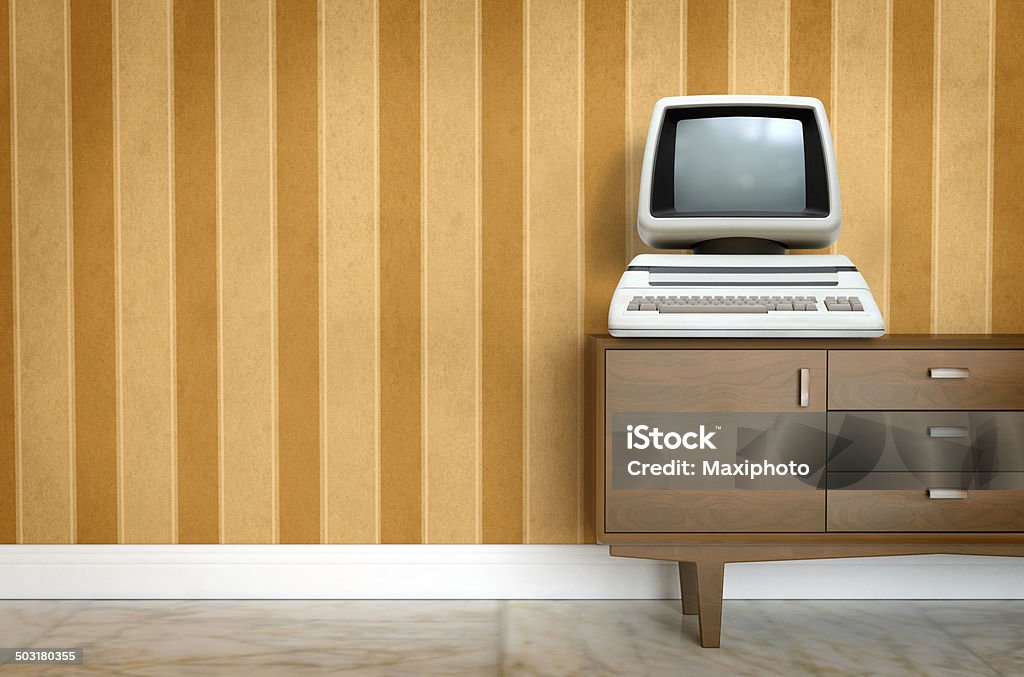 Vintage old computer on sixties, seventies wallpaper and furniture Vintage old computer from the eighties with keyboard and integrated monitor laying on a piece of old furniture and a background showing a sixties, seventies design wallpaper pattern. Copy space on the side for customization. 1950-1959 Stock Photo