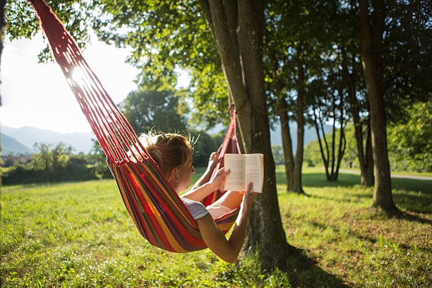 istock Young woman reading book on hammock 503187311