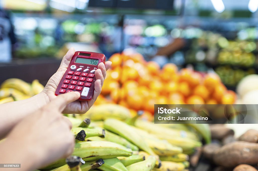 Using a calculator at the supermarket female hands holding a portable calculator at the supermarket Inflation - Economics Stock Photo