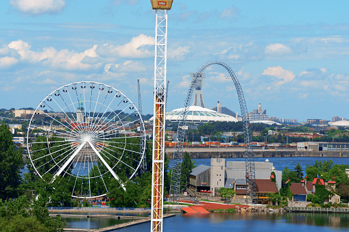 Montreal, Canada - August 09, 2008: La Ronde Amusement Park in Montreal, view from Jacques Cartier Bridge. La Ronde is the second largest Amusement Park in Canada. It was build on a little island in the middle of Saint Lawrence River in occasion of the World Expo in 1967. A lot of people walking around. In the background on the other side of Saint Lawrence River the city of Montreal and the Olympic Stadium.