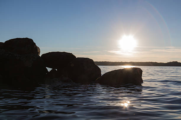 istock sun beams just above lake surface silouetting boulders 503192015