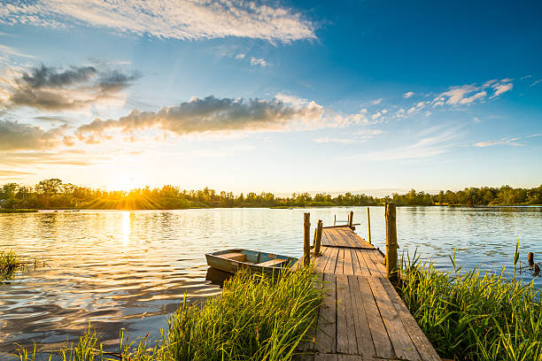 sonnenuntergang über dem see in der village - bootssteg stock-fotos und bilder