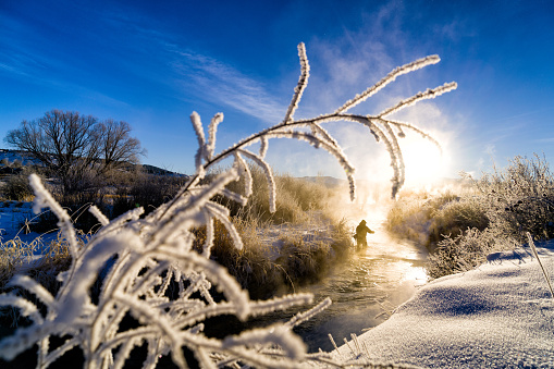 Fly Fishing in Extreme Cold Winter Conditions - Scenic winter landscape with fly fisherman recreating on cold trout mountain stream.  Colorado, USA.