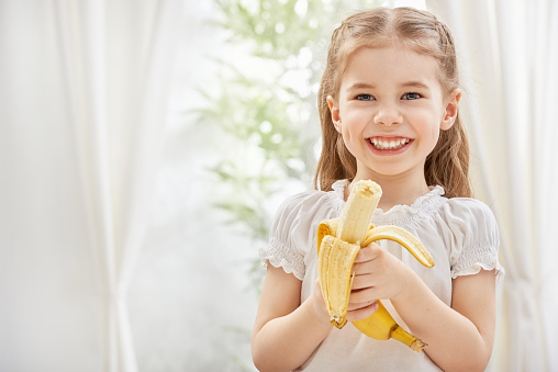 little girl holding yellow banana