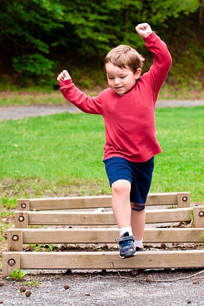 Boy jumping over obstacle on exercise course stock photo