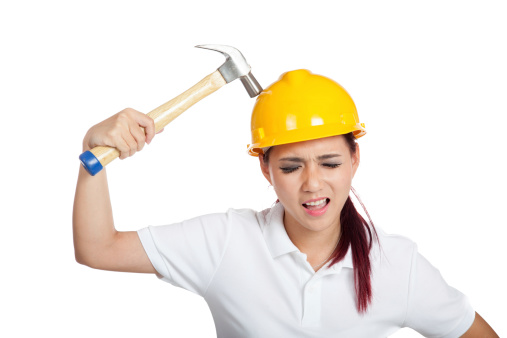 Asian engineer girl hit a hammer on her hardhat isolated on white background
