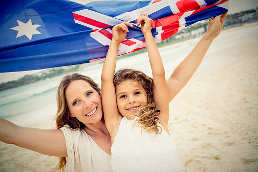 Mother and daughter with Australian flag at the beach, Australia