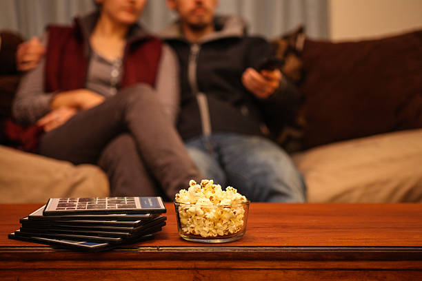 living room coffee table with movies and popcorn with couple stock photo