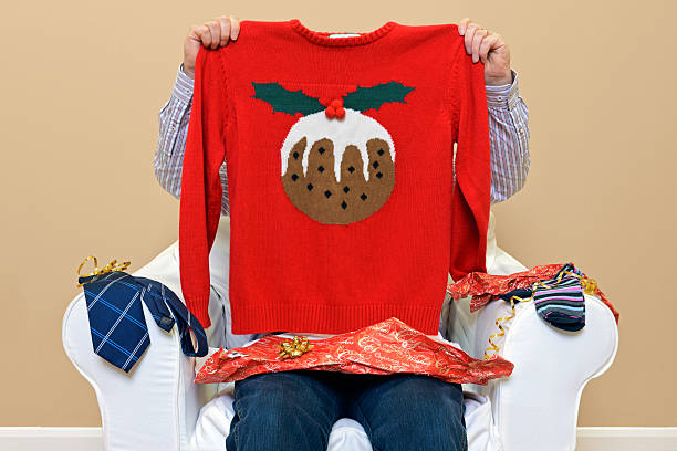 Man - Look what I got for Christmas A man opening Christmas presents to discover he got a Christmas themed jumper to go along with the usual socks and tie. christmas sweater photos stock pictures, royalty-free photos & images