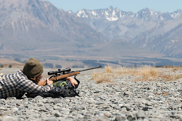 cacciatore con riffle su sfondo di montagne - rifle hunting gun aiming foto e immagini stock