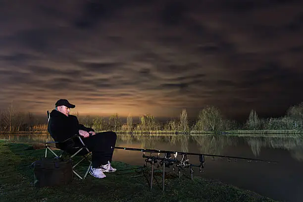 Fisherman in Beautiful night, Sitting in chair looking on rods, patience