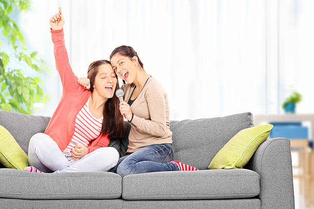 две сестры весело петь в микрофон - sofa music teenager friendship стоковые �фото и изображения