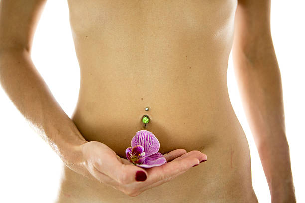 passe barriga da mulher com flor de orquídea mão a segurar. - pierced abdomen flower beauty imagens e fotografias de stock