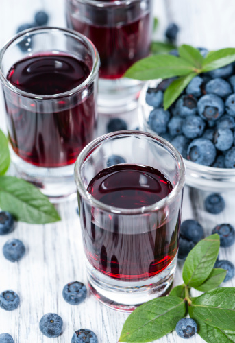 Homemade Blueberry Liqueur with fresh fruits on wooden background