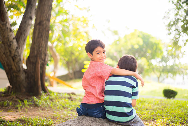 istock Little sibling boy sitting together in the park 503242284