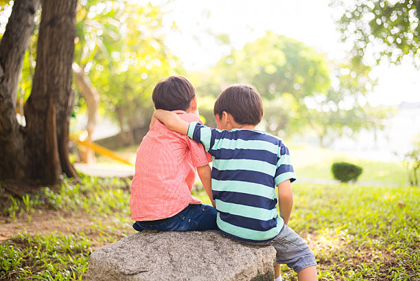 istock Little sibling boy sitting together in the park 503242362