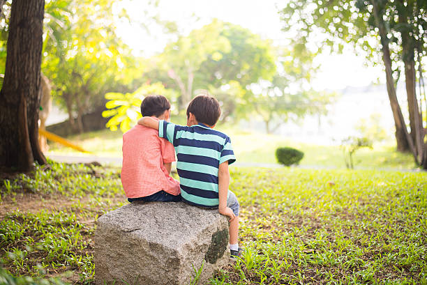 istock Little sibling boy sitting together in the park 503242632