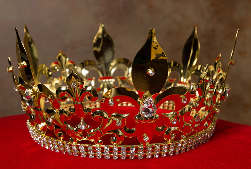 Medieval golden king's crown on red velvet pillow