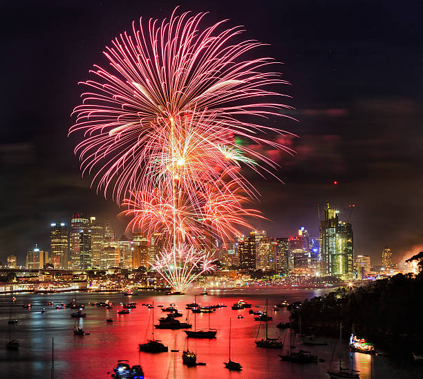 New year fireworks in Sydney from elevated lookout at Berrys bay over Sydney harbour with CBD skyscrapers under flash balls
