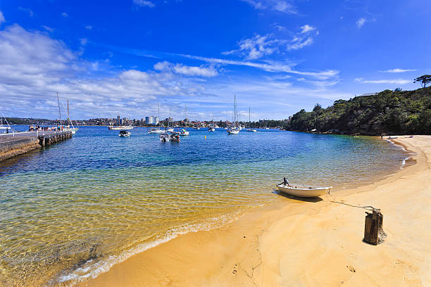 clean pristine sandy beach of quarantine station in Sydney on a summer sunny day with transparent water of harbour and wooden pier for yachts and boats