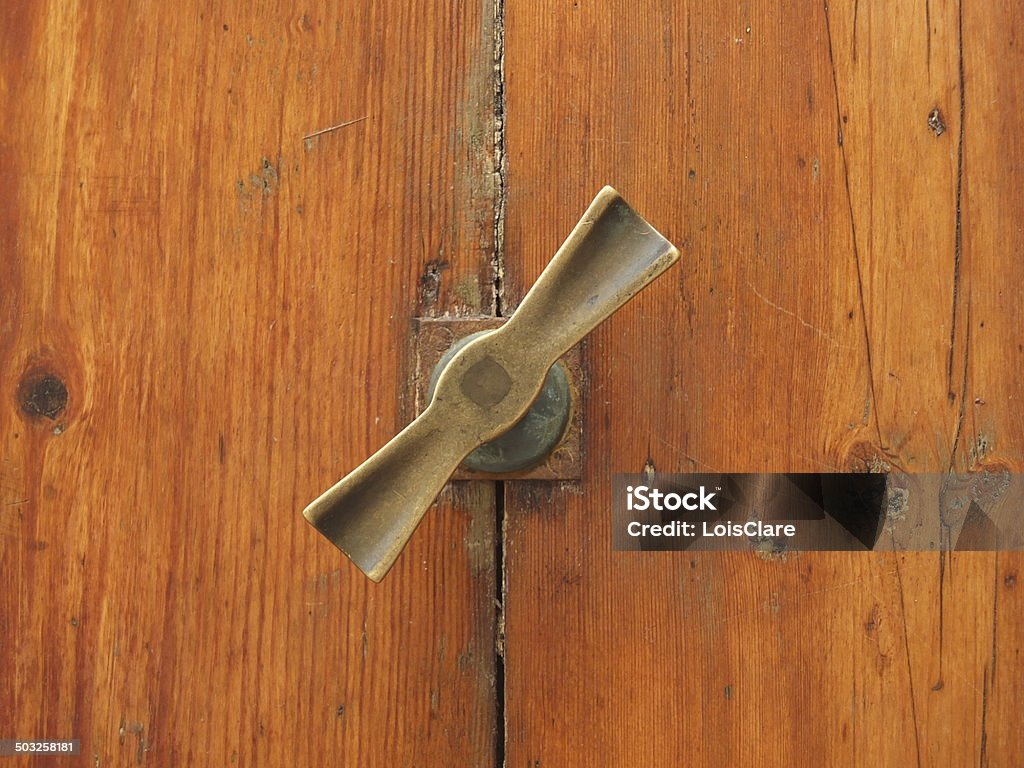 Menorcan Door Furniture On the Mediterranean, Balearic island of Menorca, the residents' front doors all have both knockers and handles to pull them closed with or to announce the arrival of visitors. The brass, some old and some weathered by years, come in all shapes and sizes, even the key holes get their own brass surrounds. Architectural Feature Stock Photo