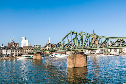 Frankfurt, Germany - March 2, 2013: people enjoy crossing river Main at the Eiserner Steg in Frankfurt, Germany. The bridge from 1868 is for pedestrians only.