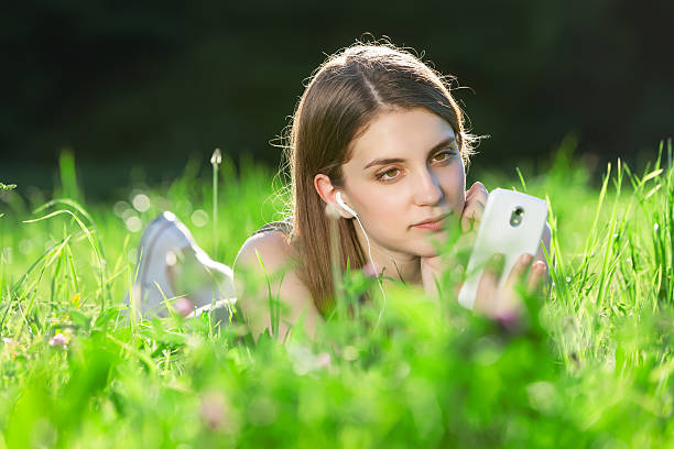 Beautiful young woman sitting on the grass in park stock photo