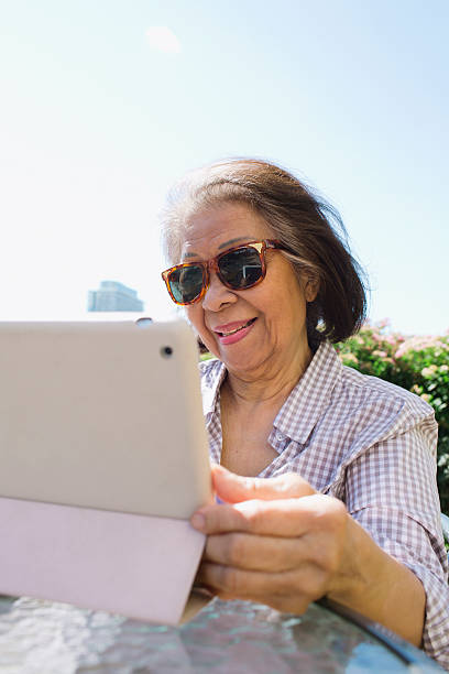 idoso sênior mulher usando um tablet de computador - solar flat panel - fotografias e filmes do acervo