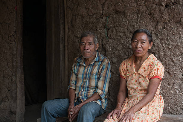 Elderly Mayan couple sits outside their house stock photo