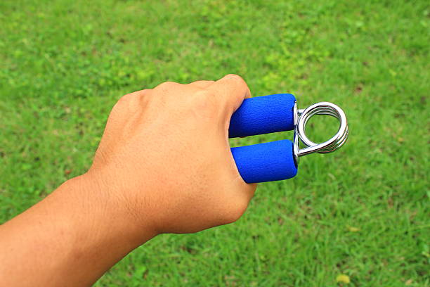 hand grip strengthener on the left hand for physiotherapy background of hand grip exercise equipment on the left hand for physiotherapy left handed catcher stock pictures, royalty-free photos & images