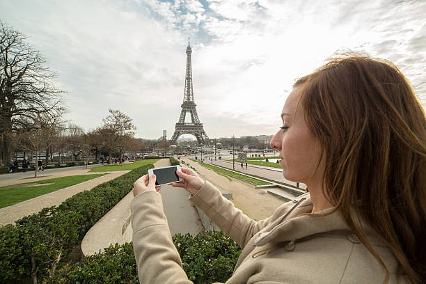 istock Young woman text messaging at the Eiffel tower, Paris 503273546