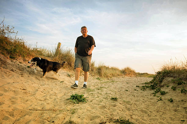 istock Senior man with dog on beach at sunset 503284891