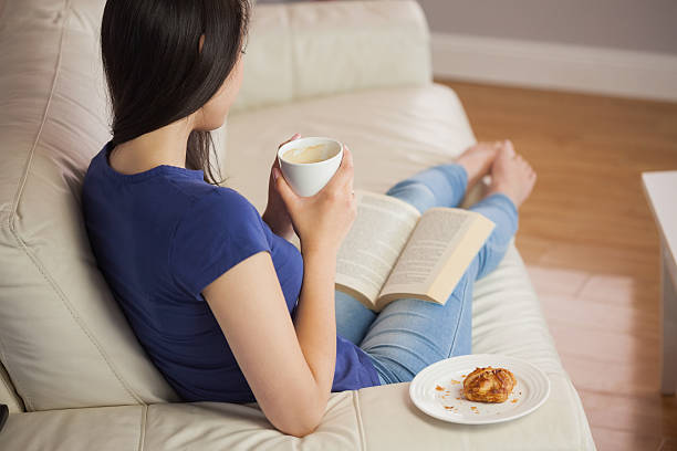 istock Young woman holding her coffee and reading book 503286875