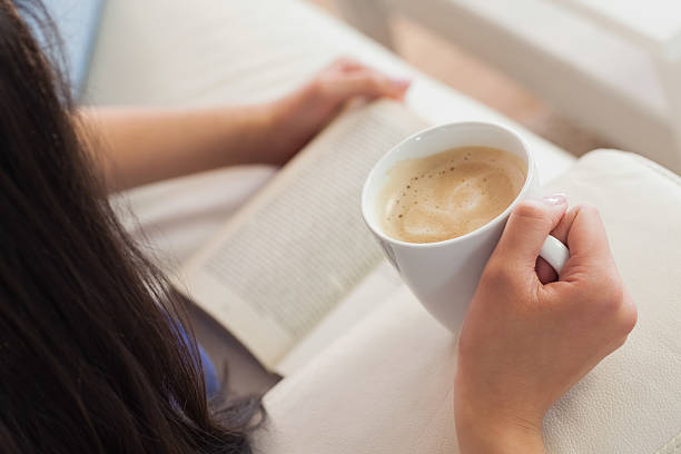 istock Woman lying on the sofa reading a book holding her 503287713