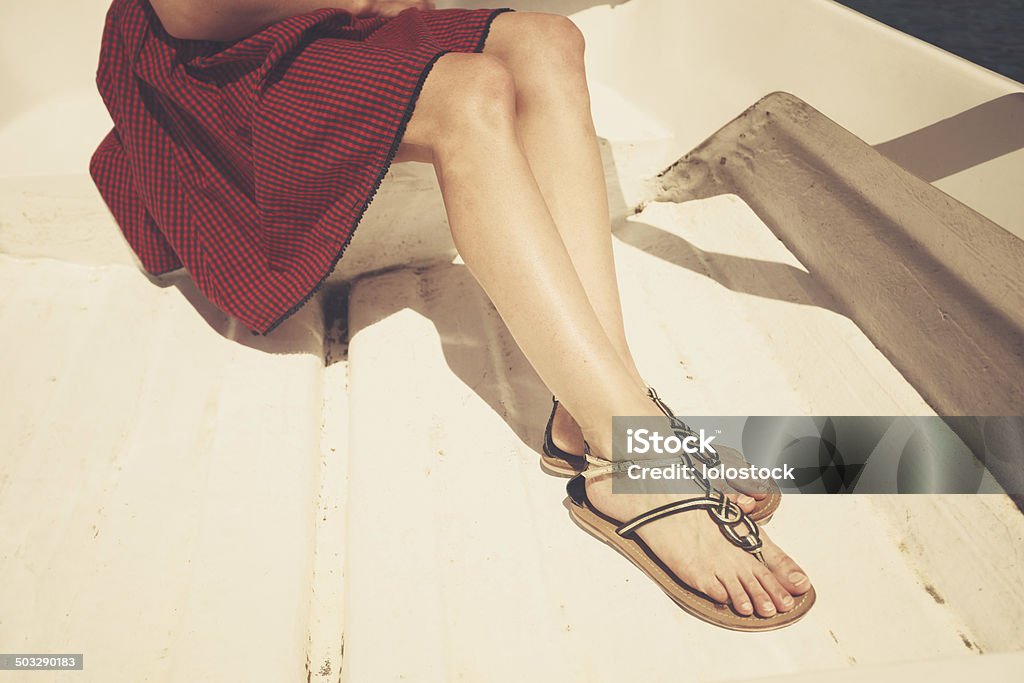 The legs of a young woman in a boat The legs and feet of a young woman sitting in a boat Sandal Stock Photo