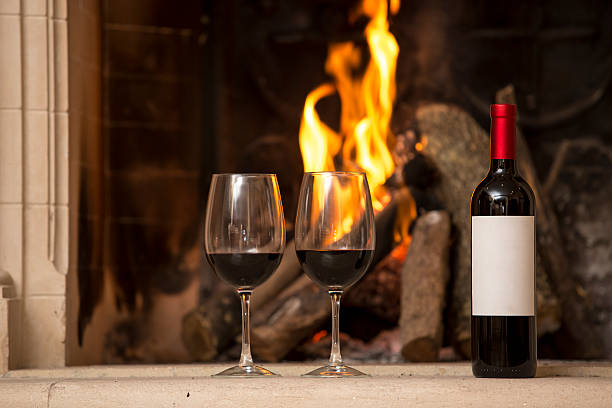 red wine bottle and cups next to the fireplace
