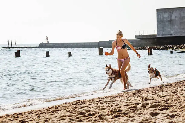 Photo of Young girl running on the beach with dog