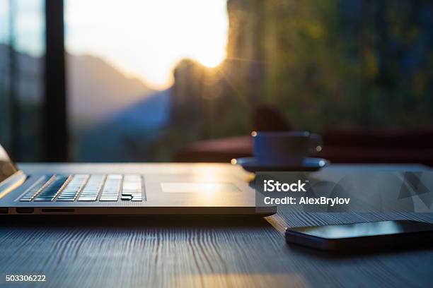 Computer Coffee Mug Telephone On Black Wood Table Sun Rising Stock Photo - Download Image Now