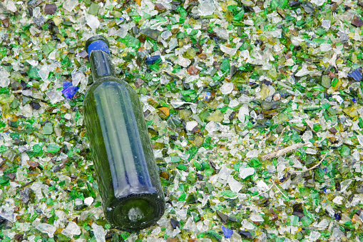 A wine bottle that has escaped the crusher lies on a bed of glass particles at an industrial recycling facility UK