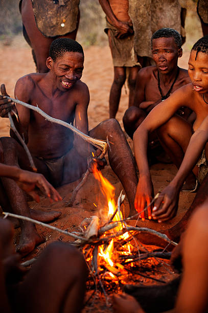 San bushmen people making fire, Grashoek, Namibia Grashoek, Namibia - August 14, 2009: Ju/'Hoansi or San bushmen people making fire in the african bush. Many tourists came to visit then in The Living Museum at Grashoek, where they perform many activities like dancing, chanting and hunting simulation. Today the San Bushmen are found only in the northwestern South Africa, northern Namibia and Botswana The bushmen are gatherer hunters living in very dry areas, their biggest stronghold is the Kalahari desert. Today the government donÂ´t allow then to hunt anymore, so they normally lives on wild fruits and roots they can find in the bush. bushmen stock pictures, royalty-free photos & images