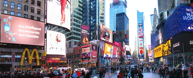 Bright lights and crowds at Times Square in New York City early in the winter morning.