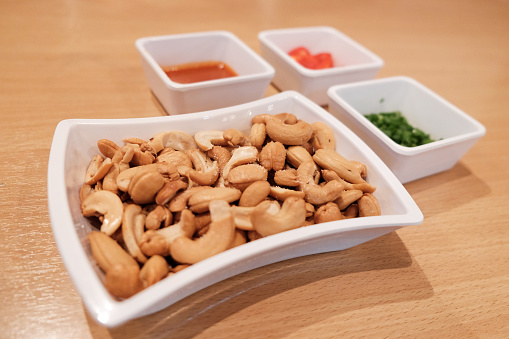 Salted cashew nuts with dippings on wooden table